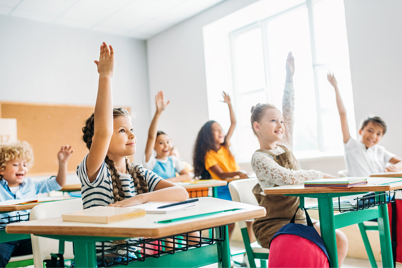 Picture of students raising their hands in a classroom